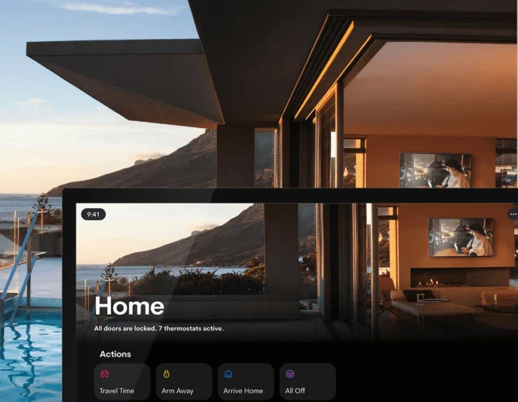 A wall-mounted smart home touchscreen controlling lighting, security and audio in a modern hillside home at sunset.