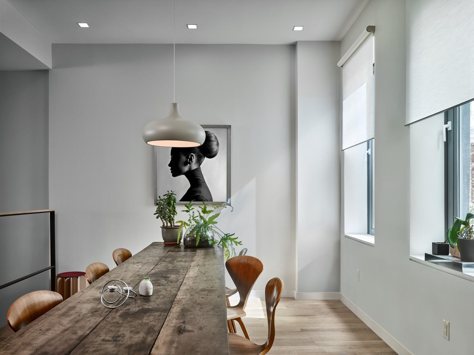 Motorised angle shades lowered over angled glazing in a loft-style dining room.