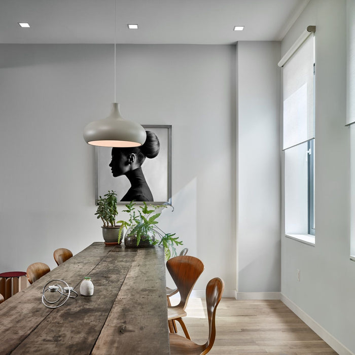 Motorised angle shades lowered over angled glazing in a loft-style dining room.