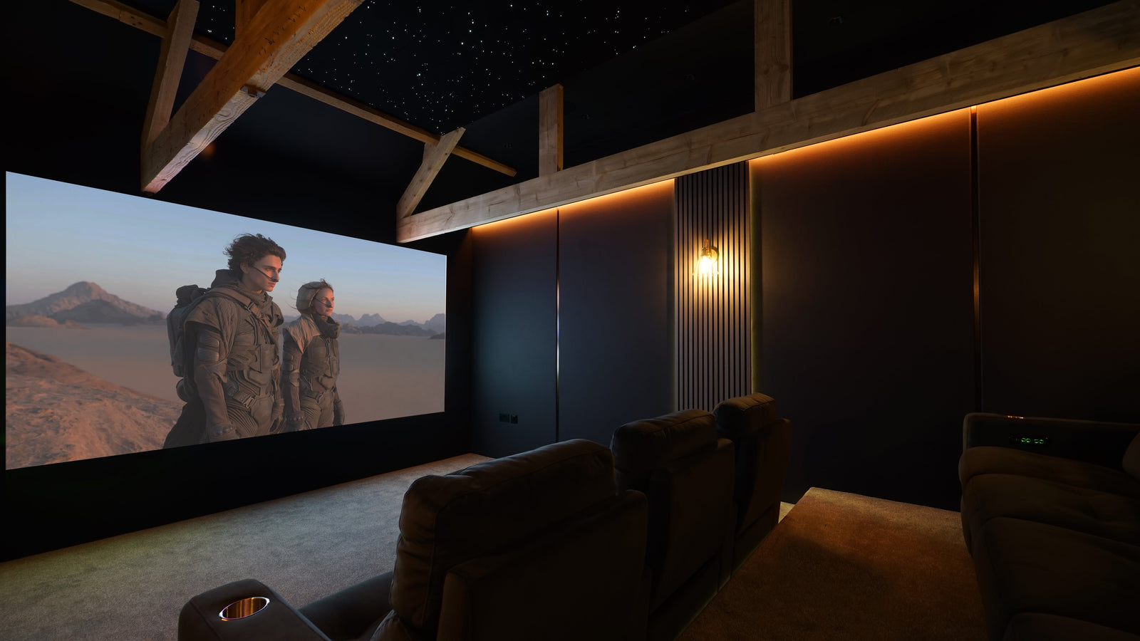 Dark dedicated home cinema with a Sony VPL-XW5000 projector, large screen and tiered seating