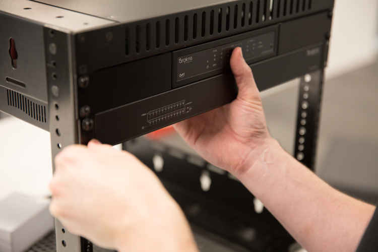 Front view of Araknis network equipment neatly installed in a professional AV rack, showing routers, switches, and cable...