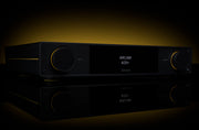 Arcam A25+ integrated amplifier in black on a reflective surface with warm amber backlighting